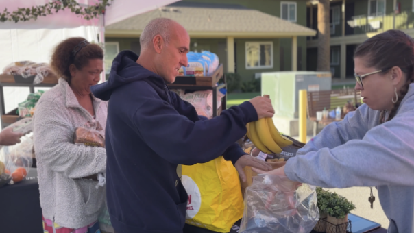A man in a blue hoodie is holding a banana.